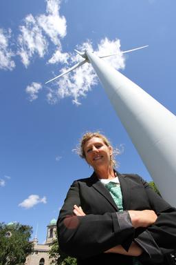 Former executive director of a green energy company stands in front of a wind turbine.