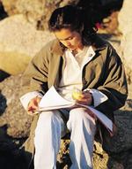 A student writes in a journal while sitting outdoors